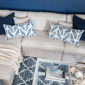 Coastal style denim blue and sustainable jute rectangle cushion in herringbone pattern on a white couch in a coastal styled living room.
