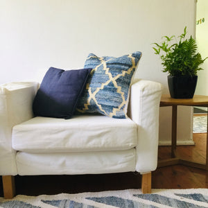 Hamptons style upcycled denim blue and sustainable jute square cushion in lattice pattern styled on white canvas lounge chair.