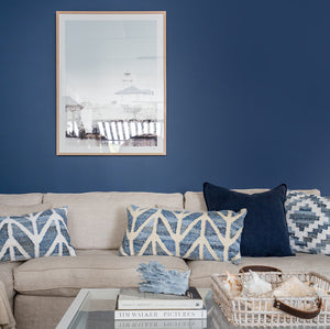 Coastal style denim blue and sustainable jute rectangle cushion in herringbone pattern on a white couch in a beach style living room.