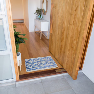 Coastal style upcycled denim blue and sustainable blonde jute door mat in herringbone pattern in an entry way front door.